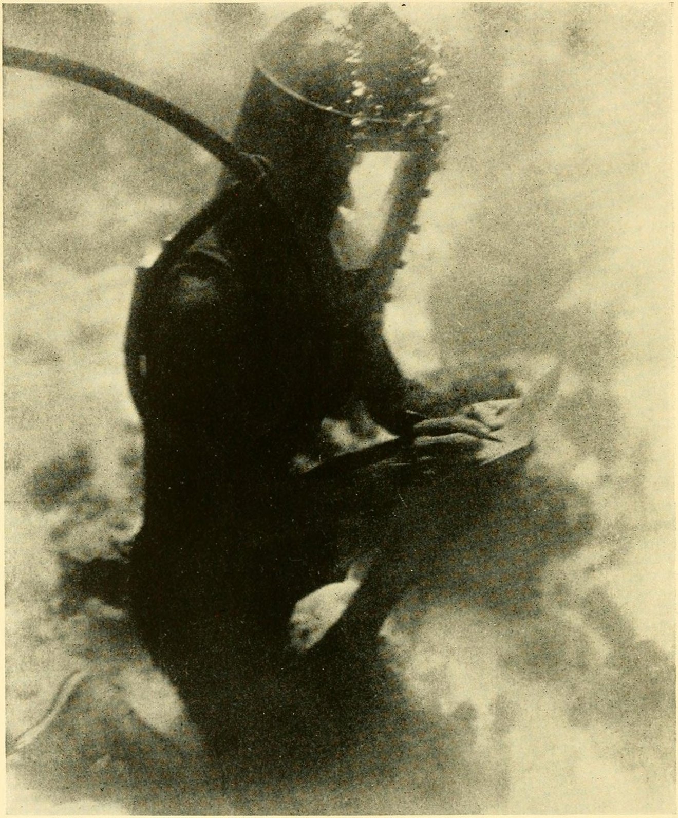 William Beebe underwater in a diving helmet, writing on a pad