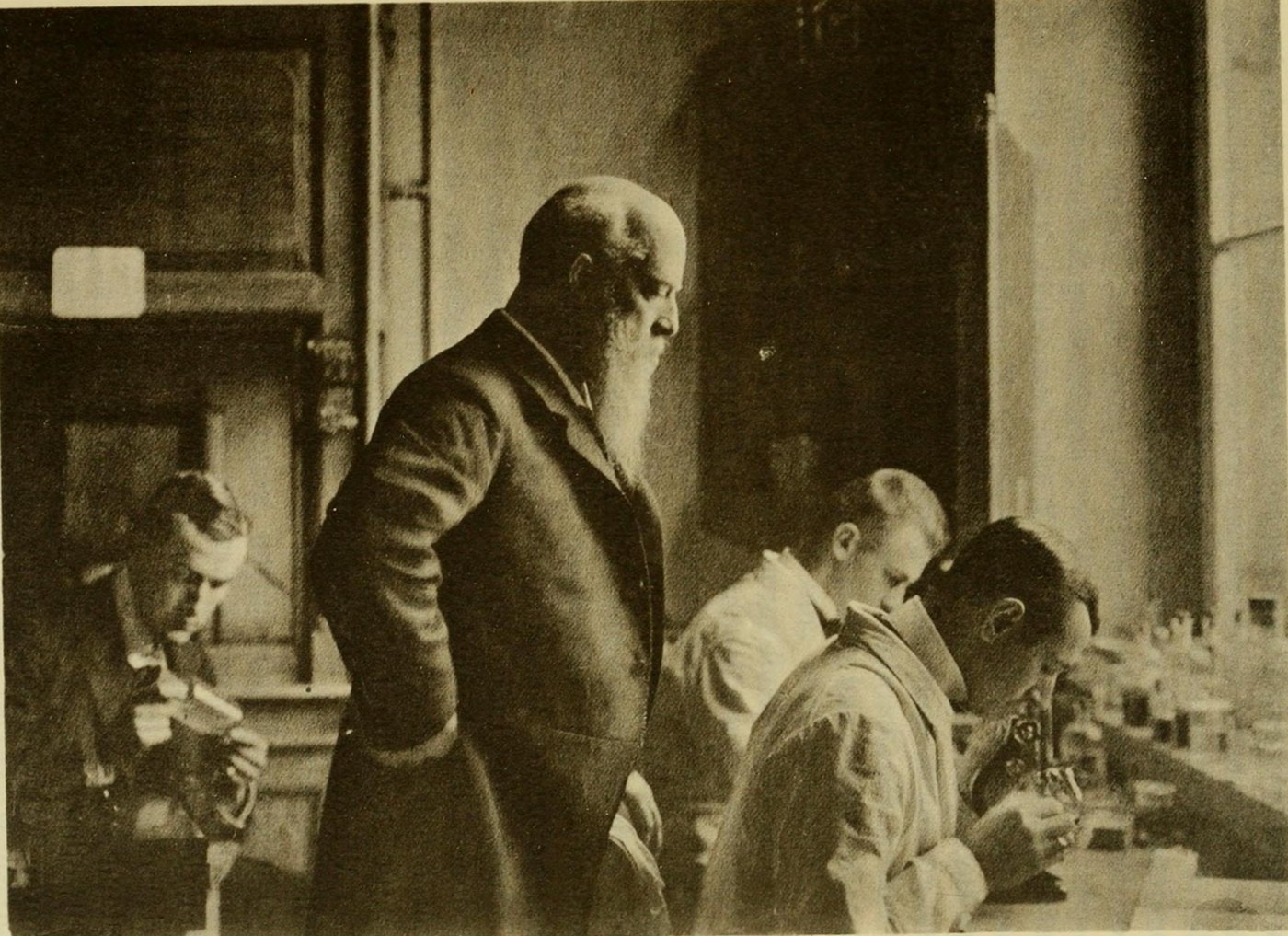 Carl Chun, white-bearded, standing among students at microscopes in a laboratory